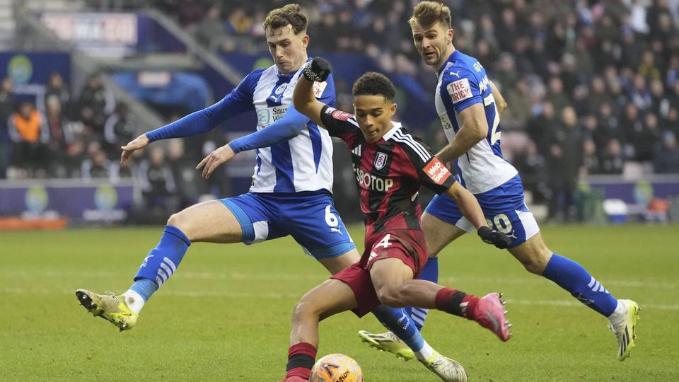Joshua King remata perante a pressão de um defesa dos Latics
