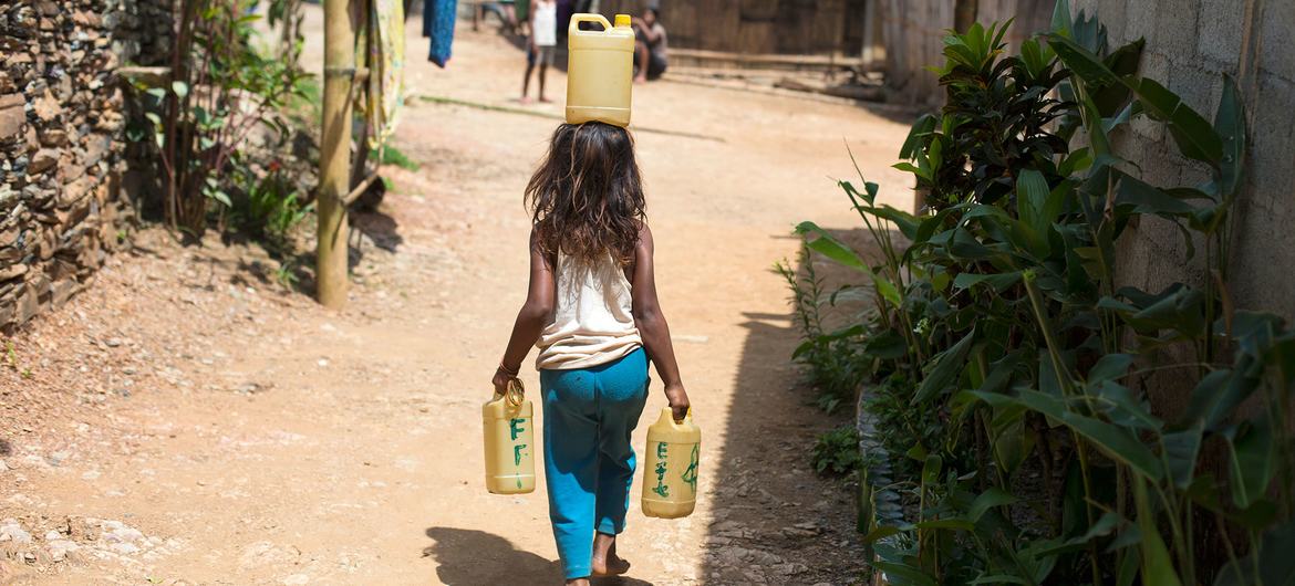 Uma menina de seis anos carrega água de uma fonte que fica longe de sua casa em Letefoho, Hatugau, município de Ermera, Timor-Leste