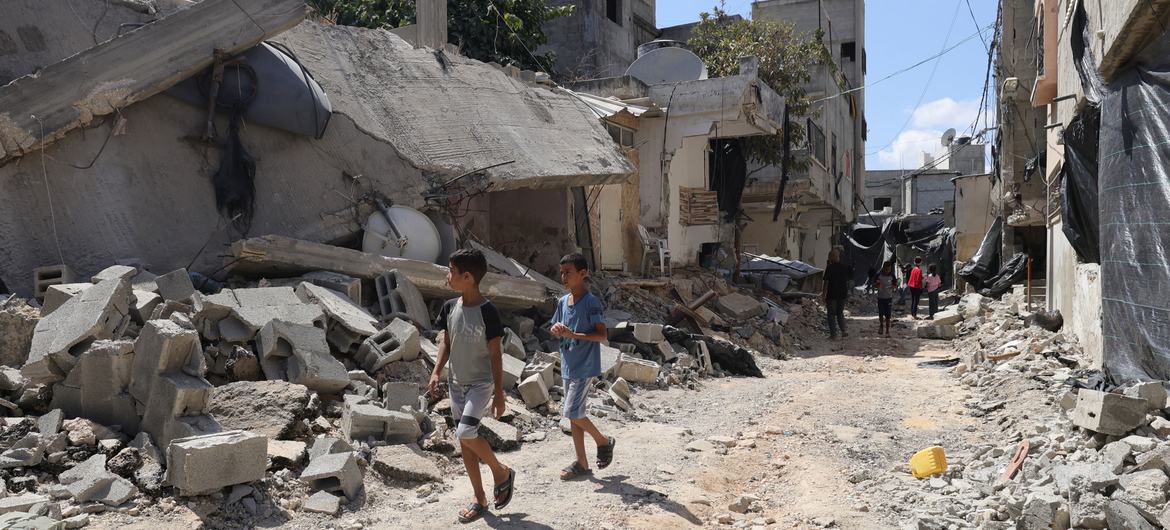 Crianças e suas famílias fogem de suas casas, caminhando entre os escombros de estradas e edifícios destruídos no campo de refugiados de Jenin, no norte da Cisjordânia