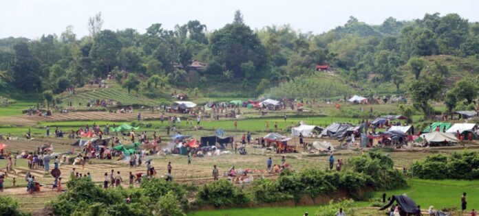 Refugiados estabelecendo abrigos temporários entre campos de arroz, após cruzarem a fronteira