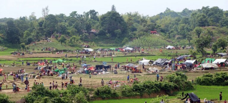 Refugiados estabelecendo abrigos temporários entre campos de arroz, após cruzarem a fronteira