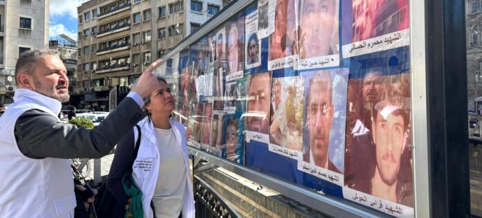 Karla Quintana (no centro), chefe da Instituição Independente, visita a Praça Al Marjeh em Damasco, um ponto focal onde famílias de pessoas desaparecidas exibem fotos na esperança de encontrar seus entes queridos