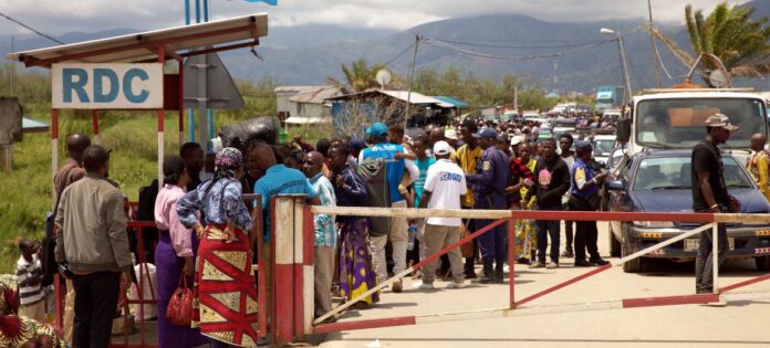 Pessoas que fogem da violência na zona de Bukavu, no leste da RD Congo, esperam para atravessar o posto fronteiriço de Gatumba para o Burundi
