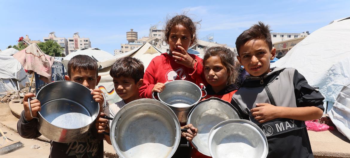 Crianças em Gaza esperando para que seus recipientes vazios sejam enchidos com comida Crianças em Gaza esperando para que seus recipientes vazios sejam enchidos com comida