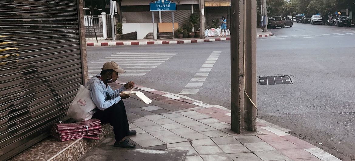 Um trabalhador do setor informal come na beira da estrada em Bangkok