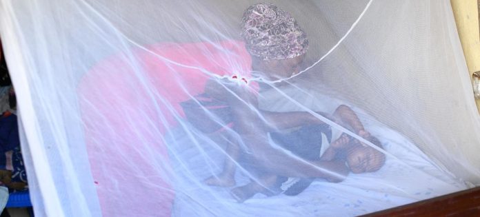 Na zona rural de Uganda, uma mãe coloca seu filho de um ano para dormir dentro de um mosquiteiro
