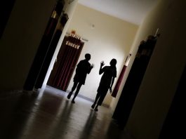 Duas meninas, de 13 e 15 anos, caminham pelo corredor para participar de uma sessão de grupo psicossocial em Dantewada, Chhattisgarh, Índia