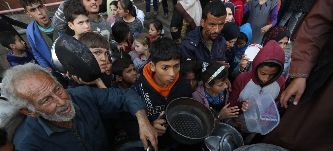 Palestinos deslocados esperam para coletar alimentos em um ponto de distribuição perto de uma escola que virou abrigo em Gaza