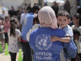 Uma funcionária da Unrwa carrega um menino em Gaza