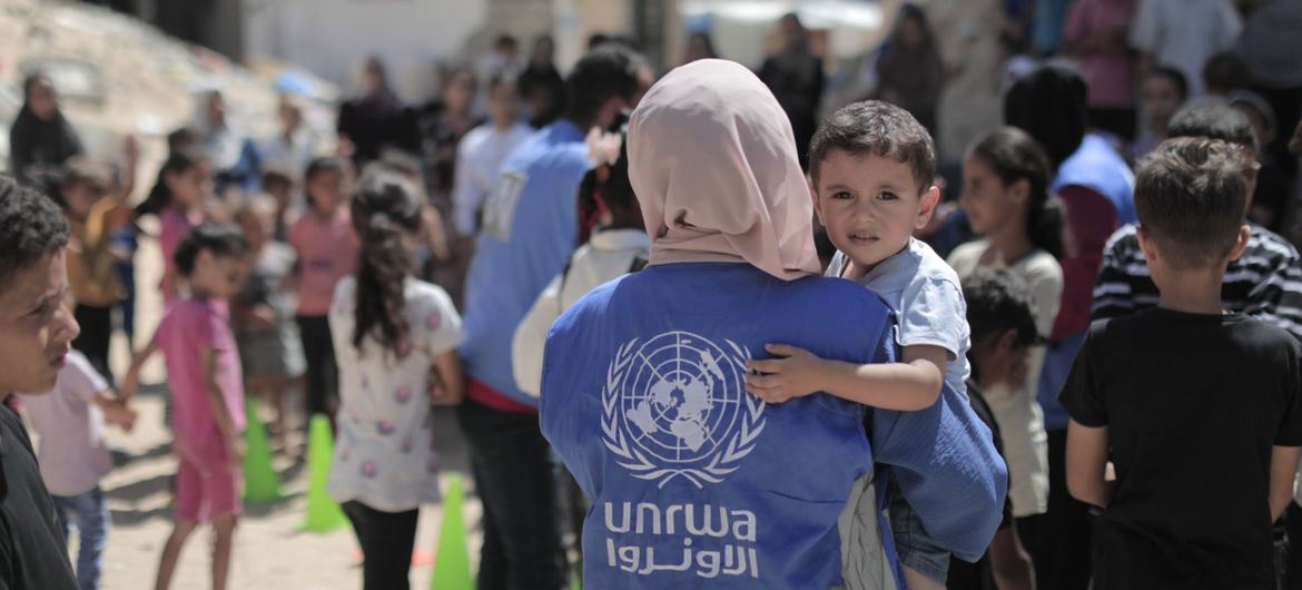 Uma funcionária da Unrwa carrega um menino em Gaza