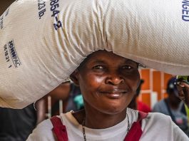 Uma mulher deslocada pela violência carrega um saco de arroz fornecido pela ONU