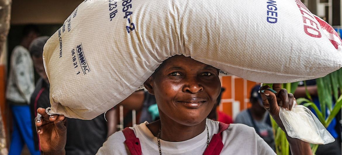 Uma mulher deslocada pela violência carrega um saco de arroz fornecido pela ONU