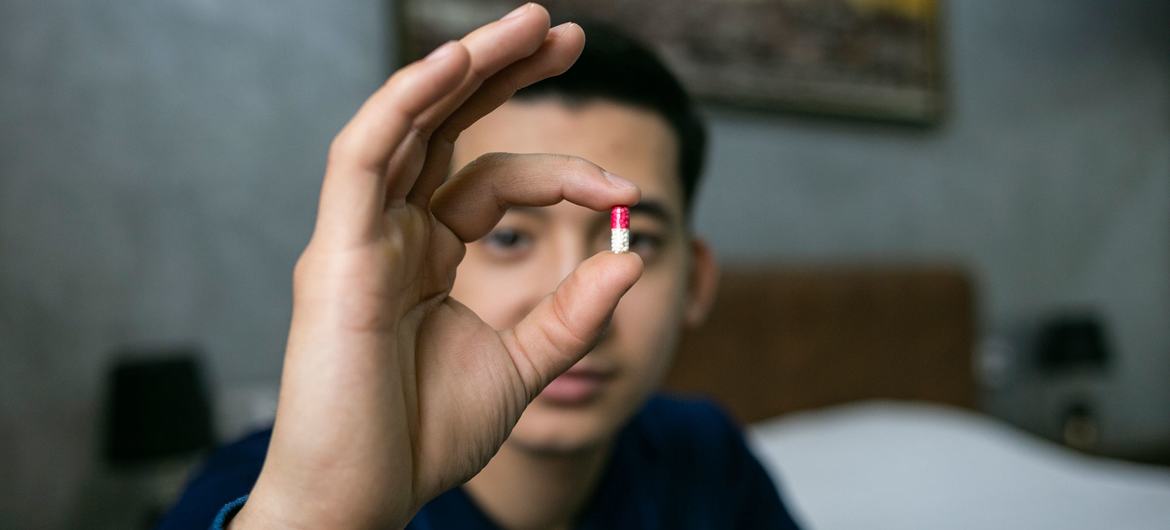 Um homem no Uzbequistão mostra o medicamento que toma para combater o HIV