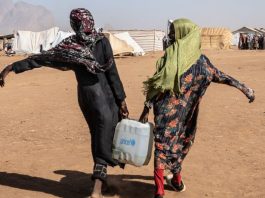 Duas mulheres carregam água em campos de refugiados