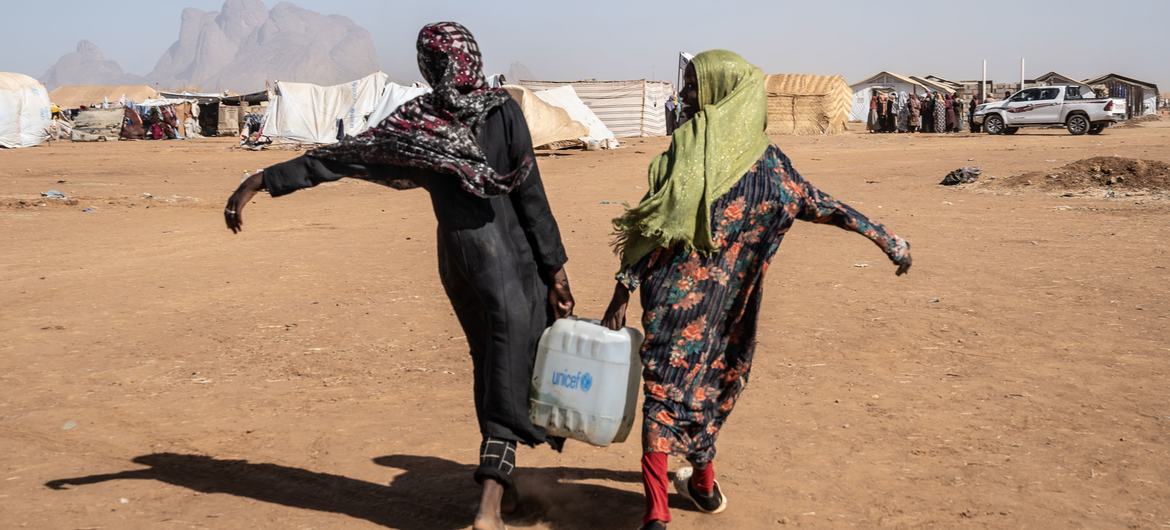 Duas mulheres carregam água em campos de refugiados