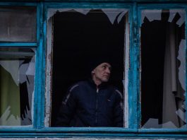 Um homem inspeciona sua janela quebrada após o projétil cair perto de sua casa em Kherson, Ucrânia