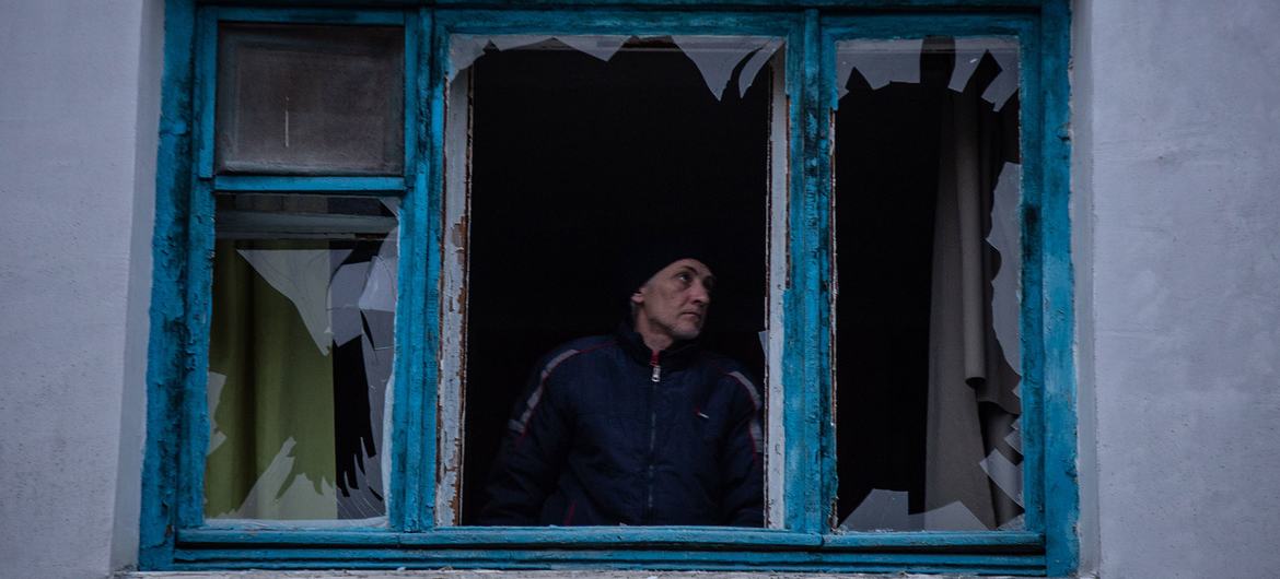 Um homem inspeciona sua janela quebrada após o projétil cair perto de sua casa em Kherson, Ucrânia