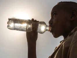 Uma criança bebe água de uma garrafa na Etiópia