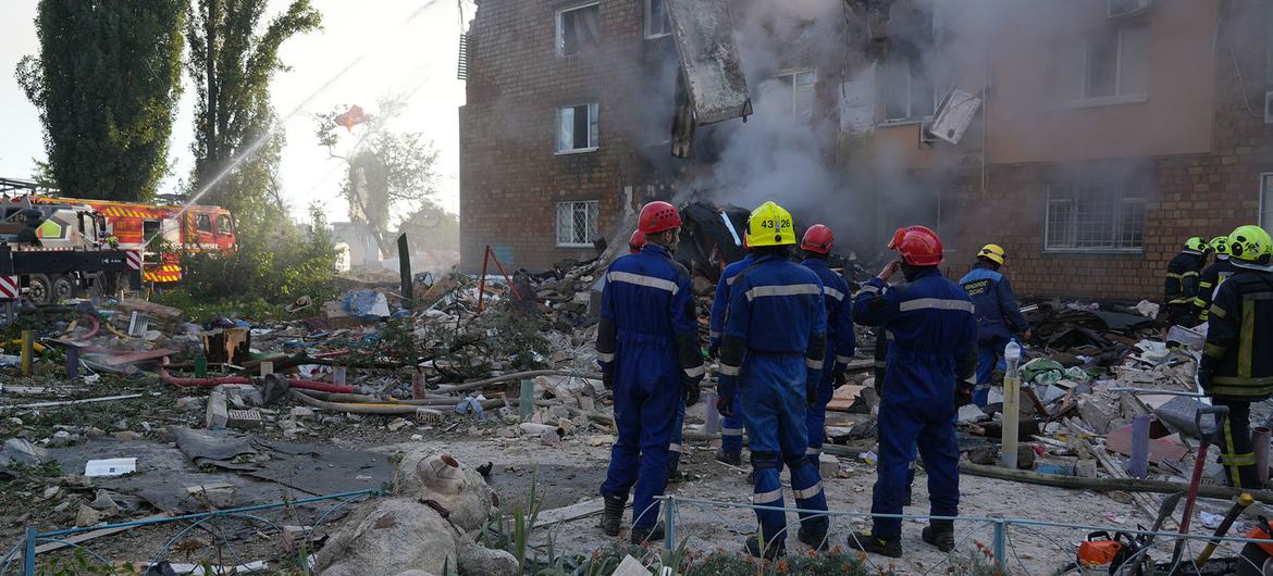 Bombeiros trabalham entre os escombros de um prédio residencial em Kyiv destruído por um ataque de míssil em 28 de agosto