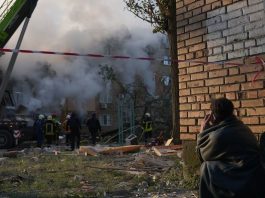Um morador perto das ruínas de um edifício residencial em Kyiv, observando as equipes de emergência procurarem por sobreviventes após um ataque de míssil nas primeiras horas da manhã de 28 de agosto