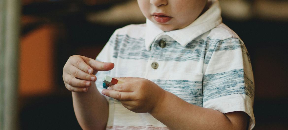 Um menino com autismo brinca com blocos de construção de brinquedo.