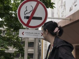 Uma mulher passa por uma placa de proibido fumar do lado de fora de um shopping center em Bangkok, Tailândia