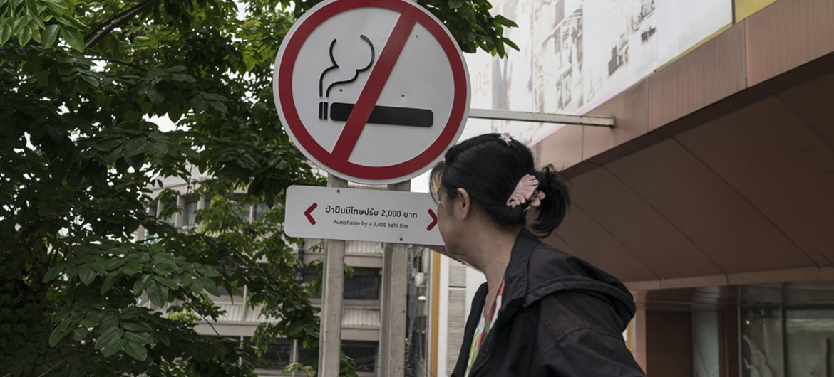 Uma mulher passa por uma placa de proibido fumar do lado de fora de um shopping center em Bangkok, Tailândia