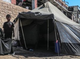 Uma família deslocada senta-se do lado de fora de sua tenda em Gaza