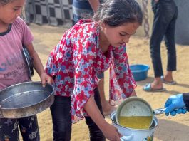 Meninas recebem comida em uma cozinha comunitária em Deir al Balah, Gaza
