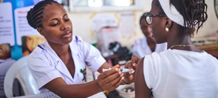 Uma profissional de saúde administra a vacina contra o HPV em uma menina em Lagos, Nigéria