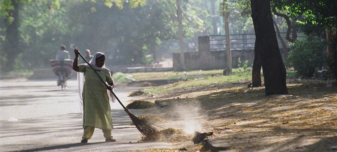 Uma trabalhadora doméstica varre a rua em um bairro nobre de Delhi, Índia Uma trabalhadora doméstica varre a rua em um bairro nobre de Delhi, Índia