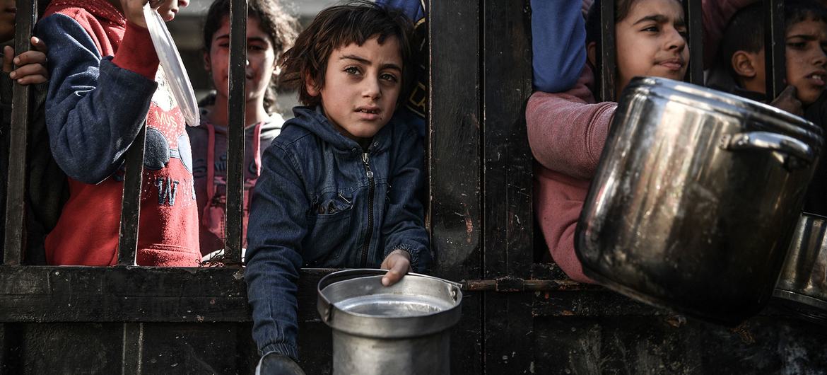 Em Gaza, as crianças esperam para receber comida enquanto os bombardeamentos no enclave continuam Em Gaza, as crianças esperam para receber comida enquanto os bombardeamentos no enclave continuam