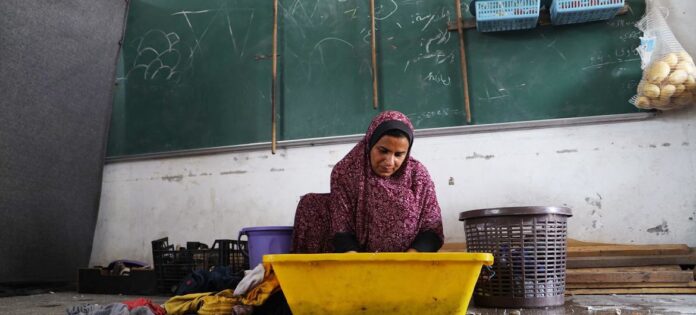 Uma mulher palestina deslocada lava as roupas de sua família em uma sala de aula em um abrigo da Unrwa em Khan Younis, no sul de Gaza.
