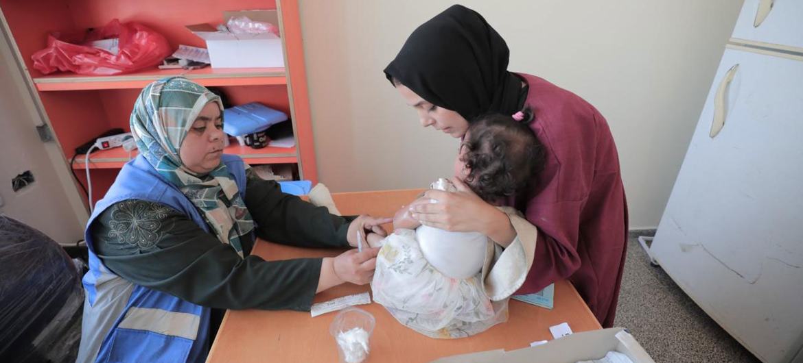 Uma mulher frequenta uma clínica de saúde com um bebê na Faixa de Gaza Uma mulher frequenta uma clínica de saúde com um bebê na Faixa de Gaza