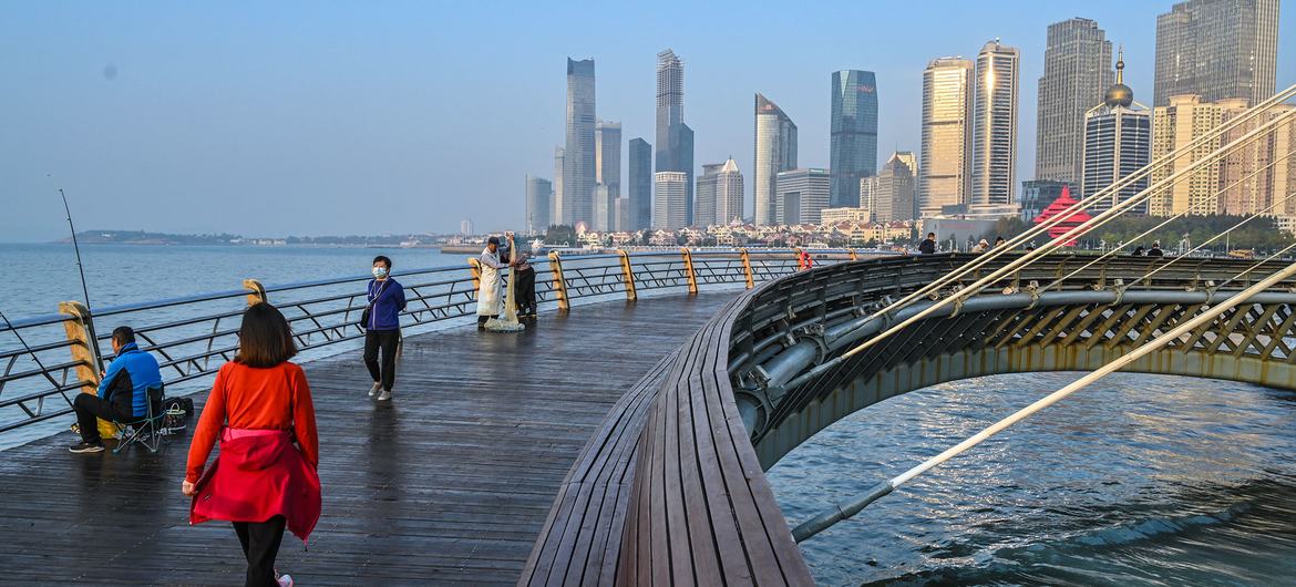 Pessoas caminham em uma ponte em um distrito de "energia inteligente e de baixo carbono" de Qingdao, na China.